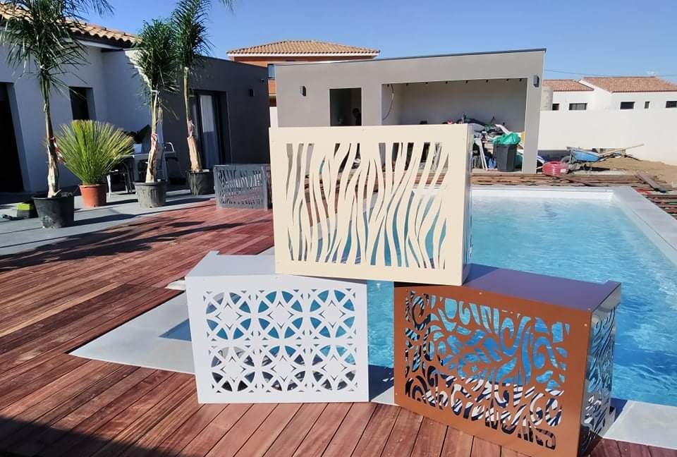 Trois cache-climatisation sur-mesure, ivoire à motif zèbre, blanc à motif géométrique et finition rouille corten, au bord d'une piscine