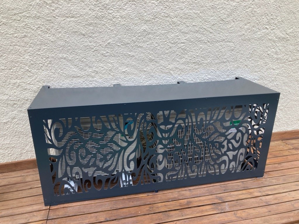 Cache-climatisation anthracite à motif végétal découpé, posé sur une terrasse bois à Saint-Laurent-de-la-Salanque